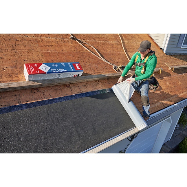 Roofer peeling the backing from GAF ice and water protective membrane on a wooden roof deck